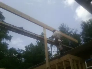 Carpenter setting a ridge beam over a new addition frame in Waterford