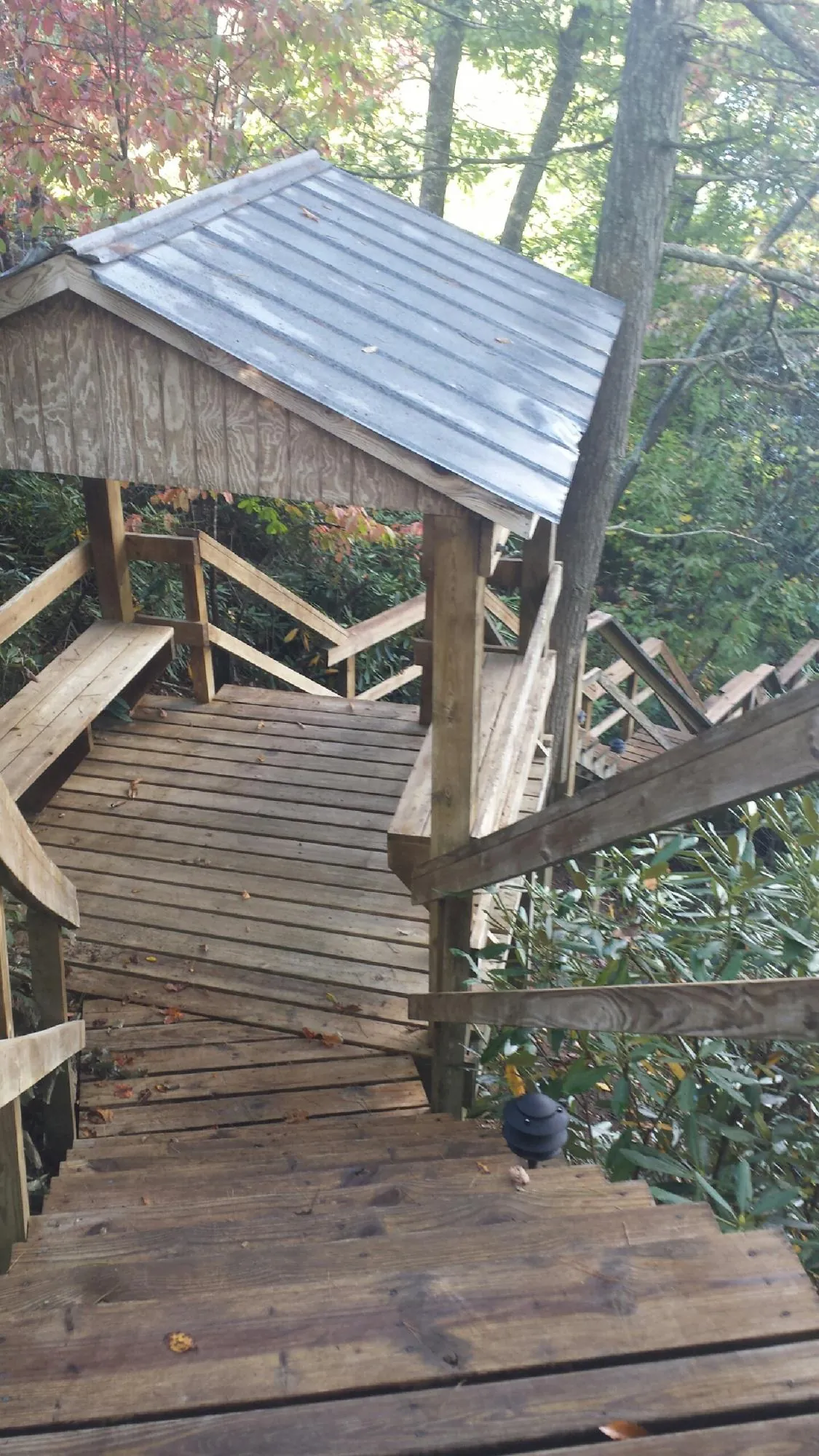 Metal roofed shelter over wooden steps on a wooded walkway — Skylight Repair & Installation work by our crew in Waterford